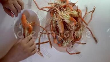 一家海鲜店里的人把煮好的虾放在盘子里。 拍摄特写。